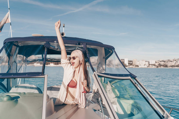 attraktives, glückliches Mädchen mit Sonnenbrille reist auf ihrer weißen Jacht in der Karibik - Foto, Bild