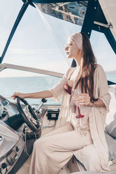a luxurious young girl enjoys a rich life, runs her yacht, drinks champagne - Foto, Imagem