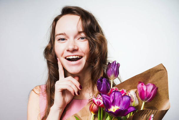 a laughing young woman enjoys the spring, holds a large bouquet of fragrant flowers, celebrates Mother's Day - Valokuva, kuva