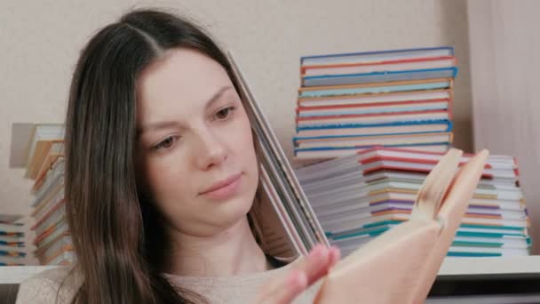 Young brunette woman looking through a book. Closeup face. - Filmagem, Vídeo