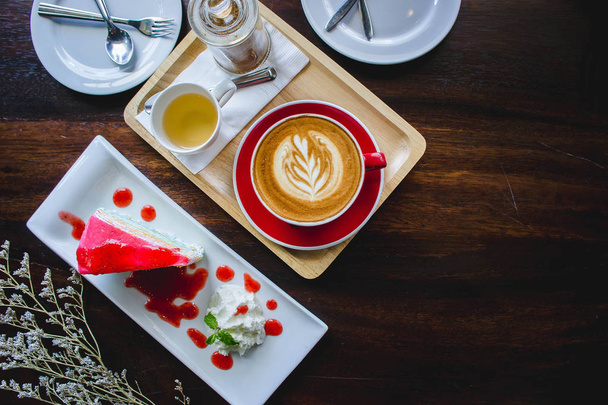 赤コーヒー カップ カフェラテ アートとコーヒー ショップのビンテージ スタイルの木製テーブルでケーキ - 写真・画像