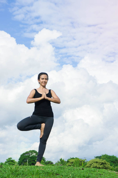Nainen harjoittelee joogaa rentoutua luonnossa ja sininen taivas tausta
 - Valokuva, kuva