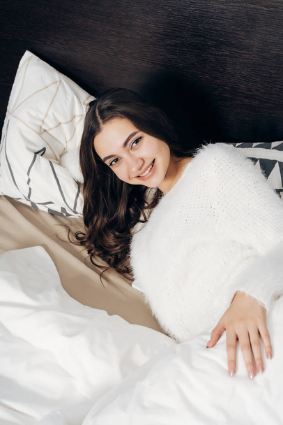 beautiful happy young girl lies in bed enjoying a good morning and smiling - Foto, immagini