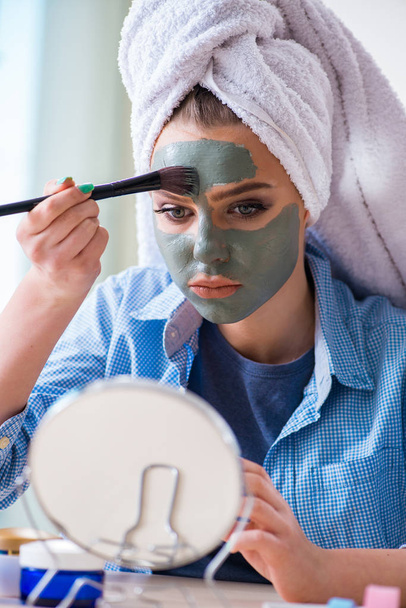 Mujer aplicando mascarilla de barro con cepillo en casa - Foto, imagen