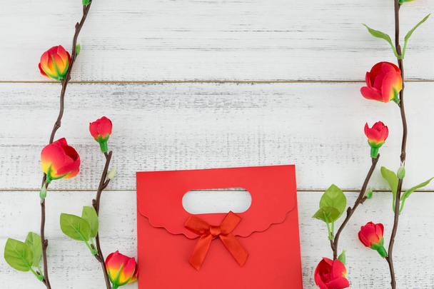 Sacchetto regalo rosso con falsi rami di fiori rossi su sfondo di legno bianco con spazio copia
 - Foto, immagini