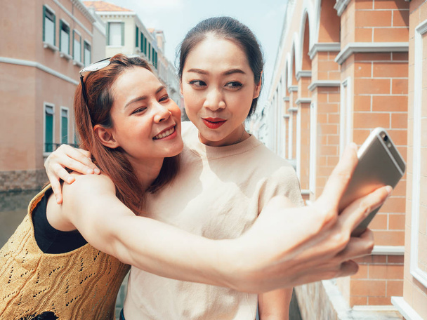 Two friends of tourist girls are taking selfie with the city vie - Photo, Image