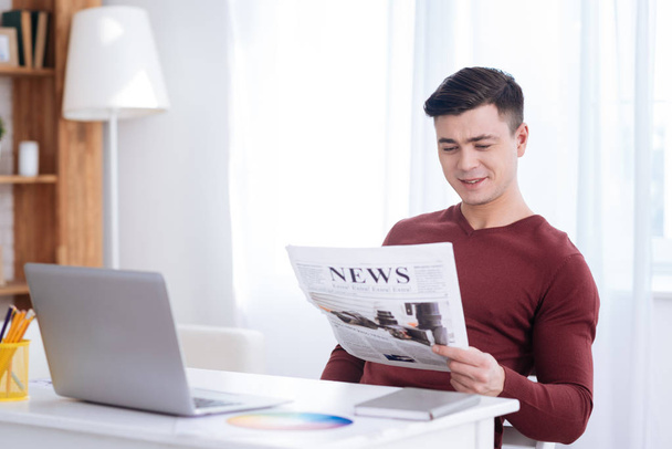 Pleasant male freelancer examining newspaper - Photo, Image