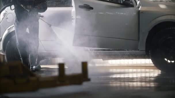 Mężczyzna robotnik czyszczenia samochodu z węża - Materiał filmowy, wideo