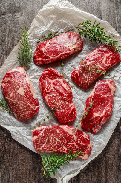 Raw bio mramorovaný hovězí steaky s rozmarýnem a tymiánem na vaření papíru - Fotografie, Obrázek