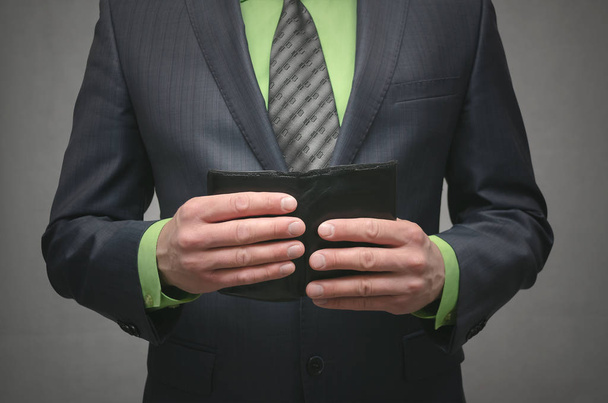 Businessman holding in hands a black leather wallet, close up photo. Customer concept. Payment. - Fotó, kép