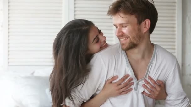 Young couple sitting on bed, beautiful woman embracing man - Séquence, vidéo