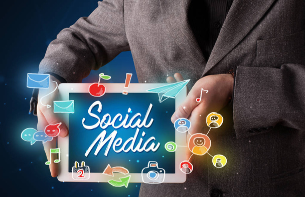 Businessman holding tablet with social media graphics - Foto, Imagem