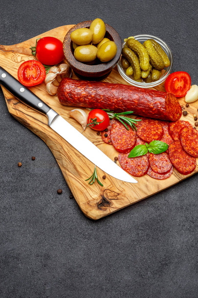 Dried organic salami sausage or chorizo on wooden cutting board - Fotó, kép