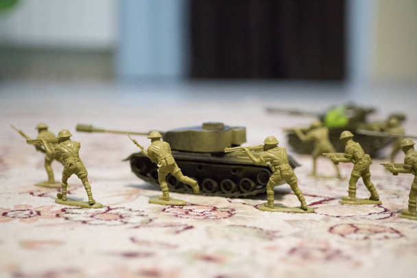 Miniatuur speelgoed soldaten en tank aan boord. Close-up beeld van speelgoed militaire in oorlog. - Foto, afbeelding