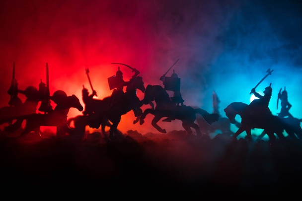 Scena di battaglia medievale con cavalleria e fanteria. Silhouette di figure come oggetti separati, lotta tra guerrieri su sfondo nebbioso dai toni scuri. Scena notturna
. - Foto, immagini