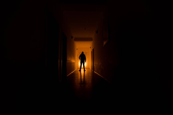 Темний коридор з кабінетними дверима і вогнями з силуетом жахливого чоловіка, що стоїть з різними пози
. - Фото, зображення