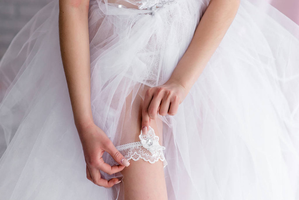 Bride wearing wedding garter. A woman demonstrates her sexy legs - Fotó, kép