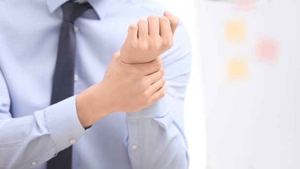 Young man suffering from wrist pain in office - Foto, afbeelding