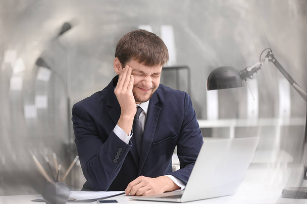 Young man suffering from headache in office - Valokuva, kuva
