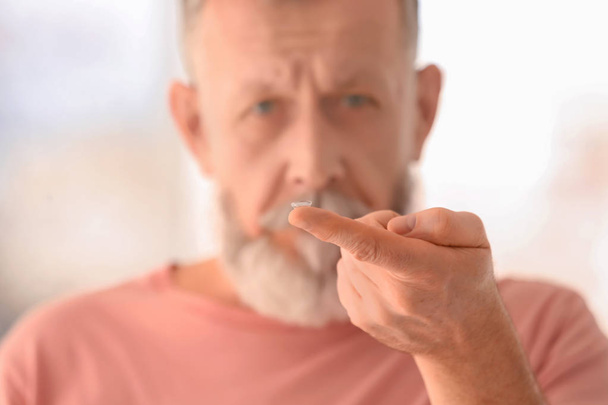 Senior man with contact lens on blurred background - Fotoğraf, Görsel
