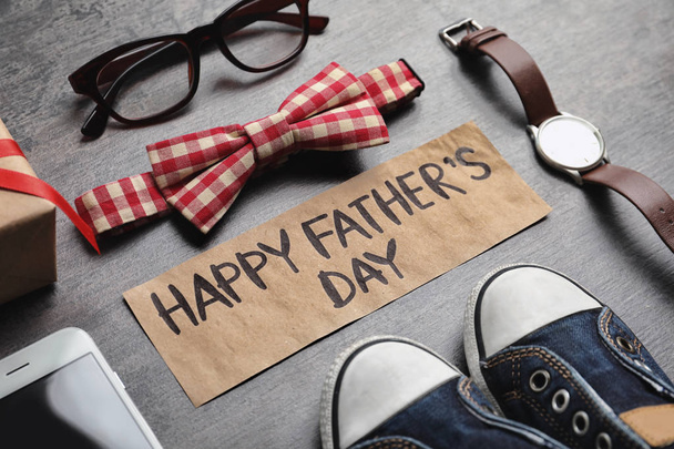 Small shoes, different gifts and card with words HAPPY FATHER'S DAY on wooden background - Фото, зображення