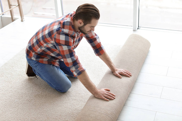 Man rolling out new carpet flooring in room - Zdjęcie, obraz
