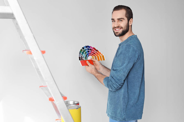 Young man with color palette on white background - Foto, afbeelding