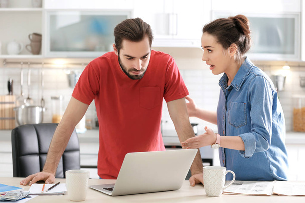 Young couple having argument about family budget in kitchen - Photo, Image