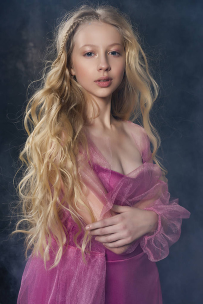Beautiful curly blonde teenager child girl wearing a pink air dr - Foto, afbeelding
