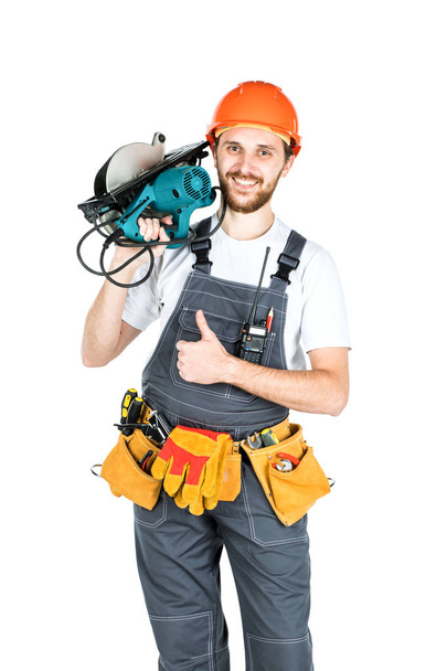 Строитель или работник в защитном шлеме с электропилой в руках. Изолированный на белом фоне
. - Фото, изображение