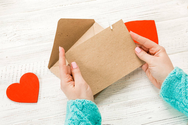 Hand van meisje liefde brief op Saint Valentines Day. Handgemaakte ansichtkaart met Rode hartvormige figuur. 14 februari vakantie feest. Valentine dag concept met kopie ruimte. - Foto, afbeelding