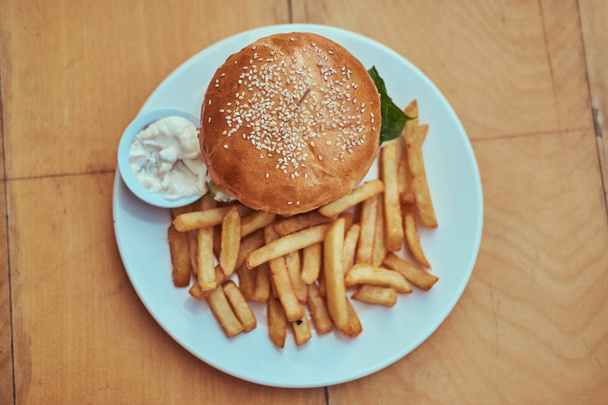 ハンバーガーとフライド ポテトとスパイシー ソース白プレートのクローズ アップ画像。不健康な食品のコンセプト. - 写真・画像