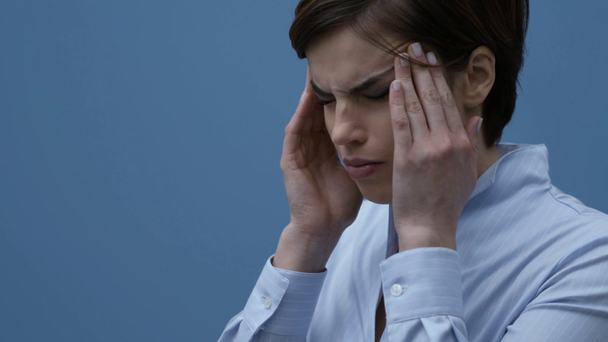 Mujer triste estresada tocando sus sienes y teniendo un dolor de cabeza fuerte
 - Metraje, vídeo