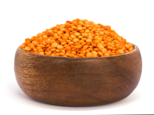 Red raw lentils in a wooden bowl. Isolated on white background - Photo, Image