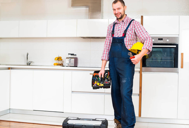 Obrero sosteniendo su caja de herramientas en la cocina
 - Foto, Imagen