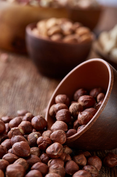 A composition from different varieties of nuts in a wooden bowls on rustic background, close-up, shallow depth of field - Φωτογραφία, εικόνα
