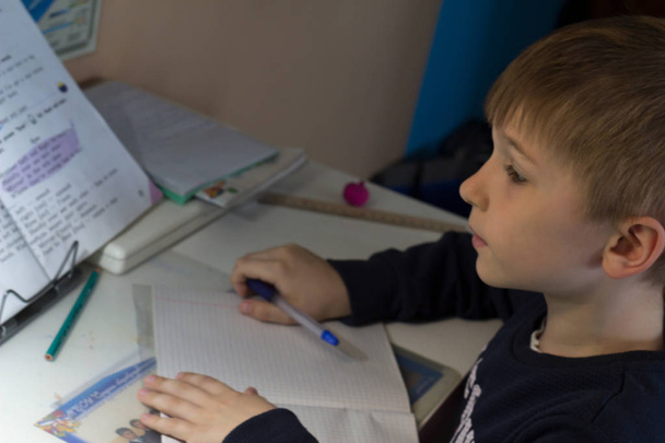 Jongen met potlood schrijven van Engelse woorden met de hand op papier van de traditionele witte Kladblok. - Foto, afbeelding