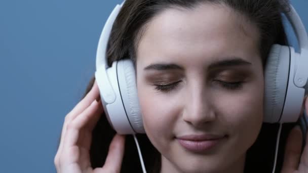 Young happy woman listening to music using headphones, she is smiling and moving - Materiaali, video