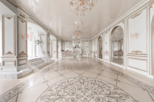 Lussuoso interno vintage con camino in stile aristocratico. Grandi finestre e specchi. Colonne e archi, ornamento sul pavimento lucido
 - Foto, immagini