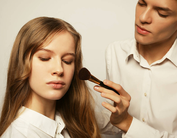 make up artist doing professional make up of young woman - Foto, Imagen