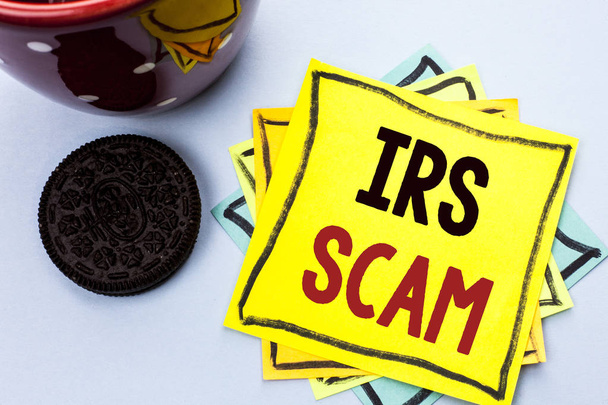 Writing note showing  Irs Scam. Business photo showcasing Warning Scam Fraud Tax Pishing Spam Money Revenue Alert Scheme written on Yellow Sticky Note Paper on the plain background Cup. - Photo, Image