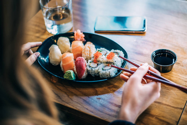 Upraw kobieta jedzenie sushi na tle - Zdjęcie, obraz