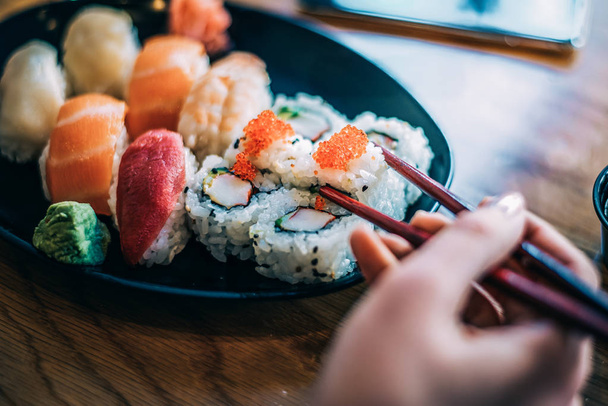 Crop woman eating sushi on background - Photo, Image