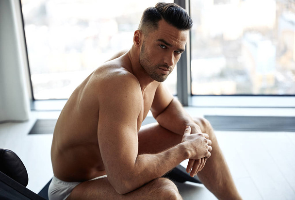 Portrait of a handsome, muscular man relaxing in an apartment - Фото, изображение