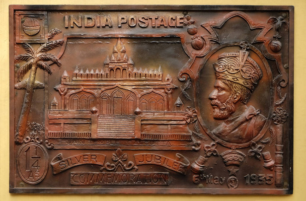 feiern silbernes Jubiläum der Krönung von König George v (1935) britische Regierung herausgegebene Briefmarke mit Darstellung des sri sital nath jain Tempels, Straßenrelief an der Wand des jain Tempels (auch Parshwanath Tempel genannt) in Kolkata - Foto, Bild