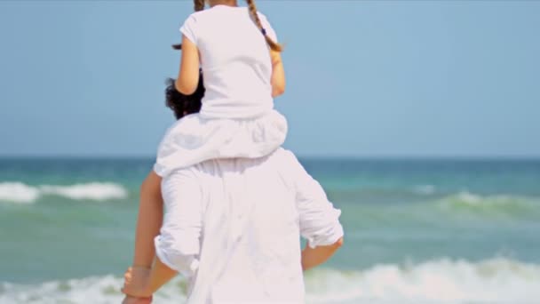 Valkoihoinen tyttö kuljetetaan isien olkapäillä rannalla
 - Materiaali, video
