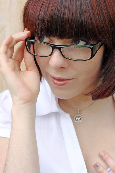 Гарненька молода жінка виглядає зацікавленою і цікавою щодо краю окулярів
 - Фото, зображення