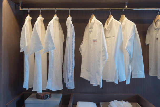σειρά από λευκά πουκάμισα σε ράγα στο ξύλινο ντουλάπι - Φωτογραφία, εικόνα