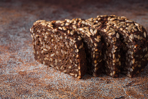 Fresh black bread with sunflower seeds on an old rusty table - Photo, Image