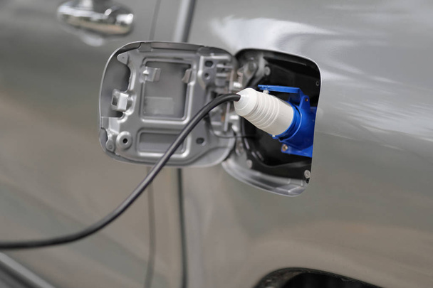 Carga de un coche eléctrico con el cable de alimentación enchufado - Foto, imagen